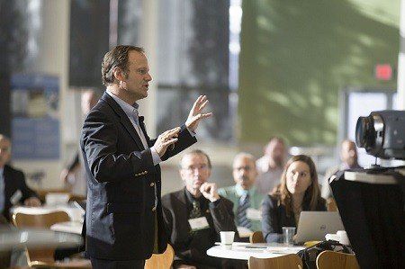 A man in a suit is giving a presentation to a group of people.